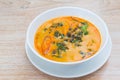 Spicy Thai Curry with River Snail and betel leaf in fresh coconut milk was served in a white bowl and put on a wooden table. ItÃ¢â¬â¢ Royalty Free Stock Photo